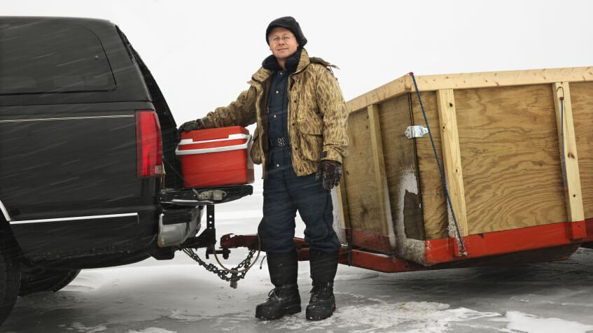 A man standing in front of a trailer hitched to an SUV