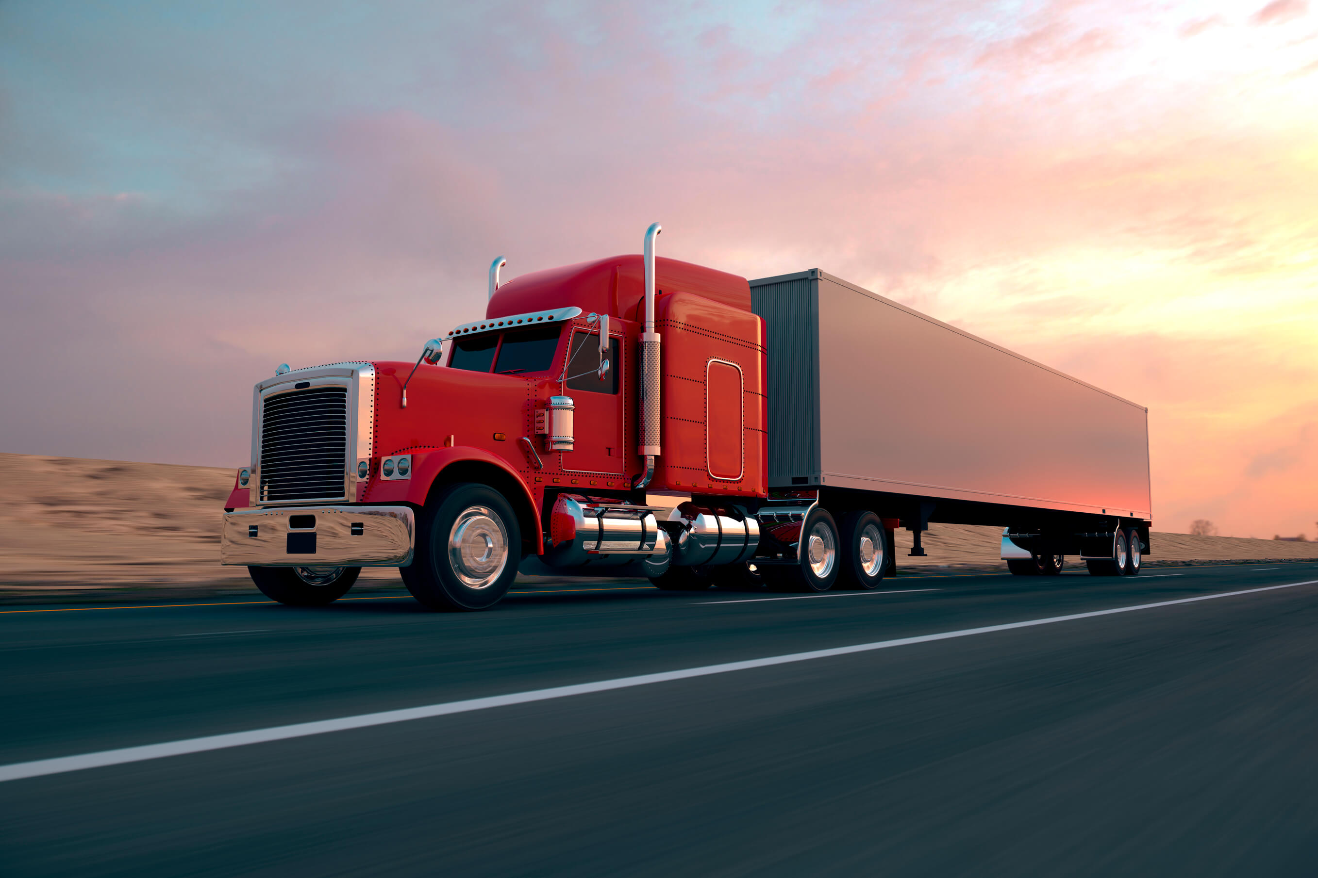 A freight truck driving on an empty highway at dusk