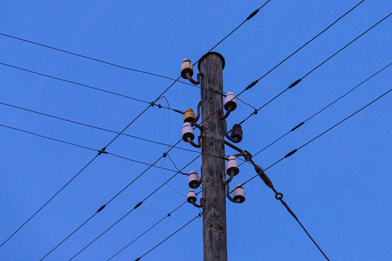 The top of a telephone pole with crossing telephone lines.