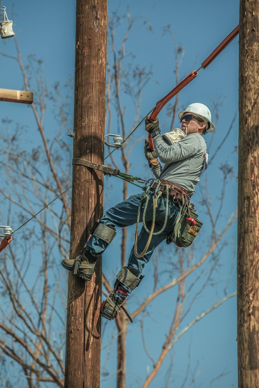 Utility company employee scaling a pole.